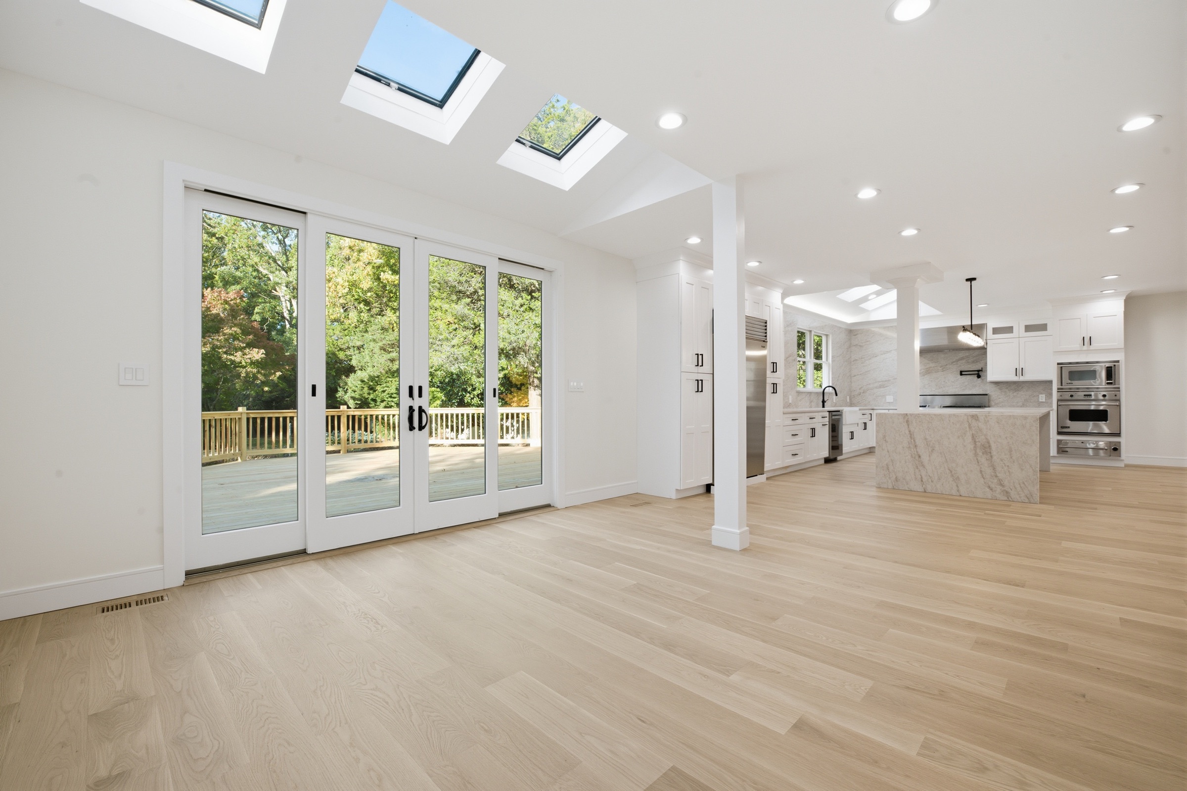 Open living area with skylights and doors to the new deck